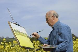 senior mannelijke kunstenaar schilderen in een veld.
