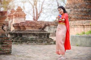 mooie aziatische vrouwen houden plastic waterpistolen vast bij een oude tempel tijdens songkran, het mooiste en leukste waterfestival in thailand foto