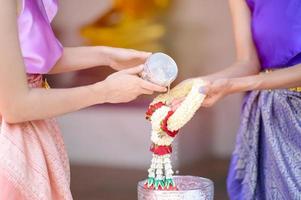 Aziatische vrouwen zegenden en gaven verse bloemenslingers aan oudere vrouwen tijdens het songkran-festival in thailand foto