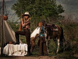 een jonge cowgirl staat met een pistool om de veiligheid van het kamp in het westen te bewaken foto
