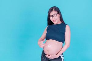 een mooie zwangere Aziatische vrouw brengt een crème aan op haar buik om striae te voorkomen foto