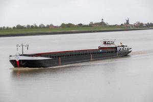 landschap met rivier en vrachtschip foto