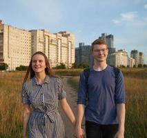 tiener paar wandelen in het veld, jongen en meisje hand in hand en glimlachen foto