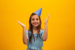 schattig klein meisje viert verjaardag. meisje klappen. close-up portret op gele achtergrond. foto