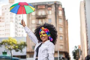 jonge vrouw met krullend haar viert het braziliaanse carnavalsfeest met frevo-paraplu op straat. foto