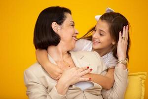 gelukkige moederdag close-up portret van mooie, charmante moeder en dochter met een stralende glimlach over gele achtergrond. dochter knuffelen moeder op gele achtergrond. foto
