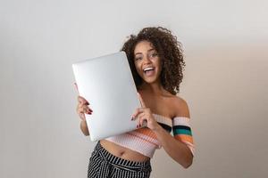 portret van lachende jonge afro-amerikaanse vrouw met laptopcomputer op witte achtergrond foto