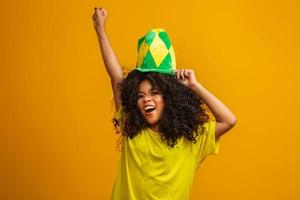 brazilie aanhanger. braziliaanse vrouw fan vieren op voetbal of voetbalwedstrijd op gele achtergrond. braziliaanse kleuren. foto