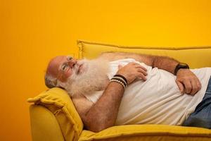 oude man met een lange baard op een gele achtergrond. senior met volle witte baard. oude man met een lange baard van verdriet. foto