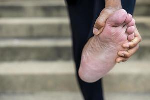 close-up van de hand van een thaise man die staat en zijn voeten buigt. foto