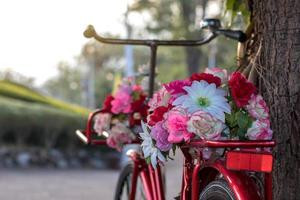 mooie kunstbloemen op een rode antieke fiets. foto