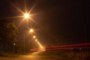 verlichting lampen en autolichten op landwegen 's nachts. foto