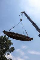 oude rottende houten boten worden verplaatst door kranen en staalkabels. foto