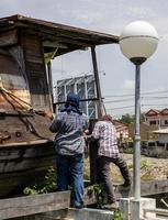 een groep Thaise mannelijke arbeiders installeert grote touwstroppen om een oude houten boot op te tillen en te verplaatsen. foto