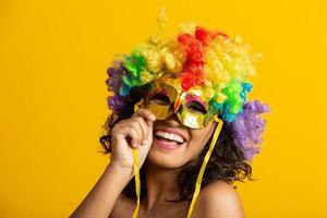 mooie vrouw gekleed voor carnaval nacht. lachende vrouw klaar om te genieten van het carnaval met een kleurrijke pruik en masker foto