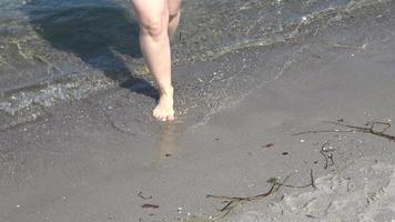 jonge vrouwelijke voeten lopen in het ondiepe water op een strand aan de Oostzee in de zomer foto