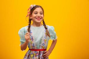 kind in typische kleding van het beroemde braziliaanse feest genaamd festa junina ter viering van sao joao. mooi meisje op gele achtergrond. foto