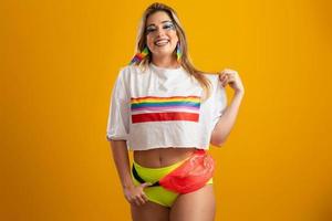 jonge blonde haarvrouw in kostuum die van het carnavalsfeest geniet dat bedekt is met lgbt-trots-t-shirt. alleen. een. lhbt-vlag. LGBT-symbool op gele achtergrond. foto