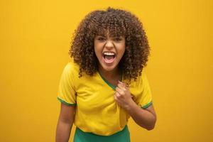 brazilie aanhanger. braziliaanse vrouw fan vieren op voetbal voetbalwedstrijd op gele achtergrond. braziliaanse kleuren. foto