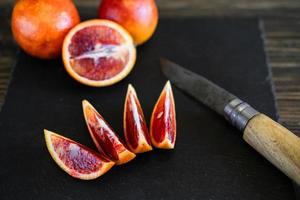 gesneden Siciliaanse of bloederige sinaasappels op een zwarte leisteen achtergrond foto