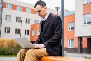 zakenman werkt buitenshuis met laptop en mobiel foto