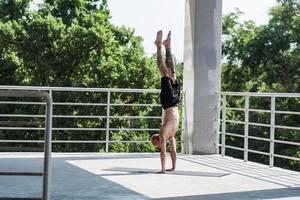 jonge man met tatoeages doet yoga-oefeningen buiten op balkon foto