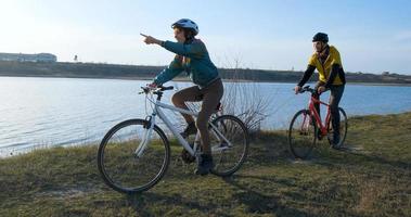 paar mannelijke en vrouwelijke fietsen in de buurt van de rivier tijdens zonsondergang foto