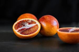 gesneden Siciliaanse of bloederige sinaasappels op een zwarte leisteen achtergrond foto
