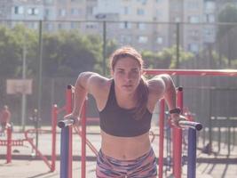 jonge sterke vrouw die in de zomer buiten traint, vrouwelijke professionele atleet doet oefeningen in het park foto