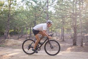 jonge atleet rijdt op zijn professionele berg- of cyclocrossfiets in het bos foto