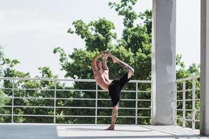 jonge man met tatoeages doet yoga-oefeningen buiten op balkon foto