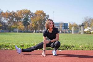 jonge vrouwelijke hardloper die in de zomerdag buiten op het studium traint foto