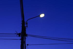 elektriciteitspaal en kabellijn met straatlantaarn 's nachts foto