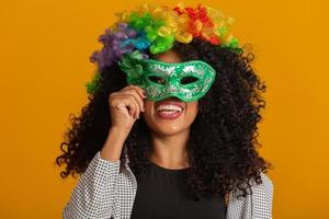 mooie vrouw gekleed voor carnaval nacht. lachende vrouw klaar om te genieten van het carnaval met een kleurrijke pruik en masker foto