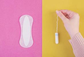 hygiënische zorg tijdens kritieke dagen. kiezen tussen een tampon en een maandverband. menstruatiecyclus. de vrouw houdt in handen van een tampon. bovenaanzicht foto