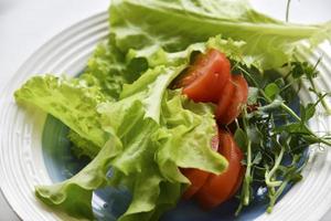 salade op een witte plaat tomaten greens en erwten. witte achtergrond. foto