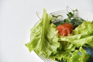 salade op een witte plaat tomaten greens en erwten. witte achtergrond. foto