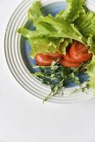 salade op een witte plaat tomaten greens en erwten. witte achtergrond. foto