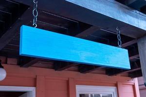 blauwe houten plank hangend aan de ingang van de winkel. schoon oppervlak voor logo- of naampresentatie foto