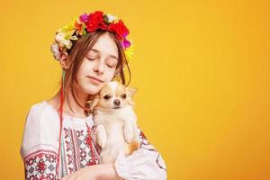 tienermeisje met een krans op haar hoofd en gekleed in een geborduurd shirt met een chihuahua-hond. huisdier. foto