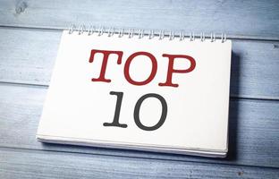 top 10 teken op het witte notitieblok op het blauwe houten bureau foto