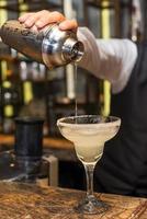 barman aan het werk, cocktails bereiden. margarita gieten in cocktailglas. foto