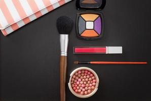 cosmetische producten en make-up accessoires op zwarte achtergrond. bovenaanzicht en kopieer ruimte. zomerse kleuren. borstel, lippenstift, oogschaduw. foto