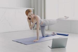 vrouwelijke coach heeft videoles. jonge atleet die yoga beoefent. personal training door middel van videolessen. foto