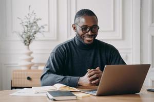 positieve Afro-Amerikaanse mannelijke privéconsulent die online sessie heeft, luistert aandachtig naar de klant foto