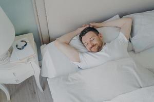jonge gelukkig ontspannen blanke man slapen in bed foto