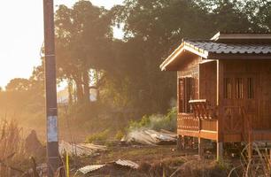 klein houten huis met zonneschijn op het thaise platteland. foto