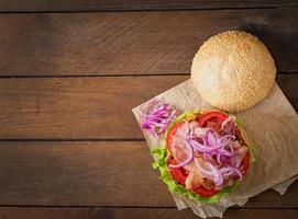 grote sandwich - hamburgerburger met rundvlees, rode ui, tomaat en gebakken spek. foto