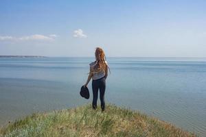 minimalistisch landschap met kleikliffen en zee en jonge vrouwelijke wandelaar foto