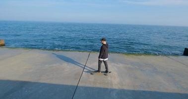 jonge man met skateboard ontspannen in de buurt van zee foto